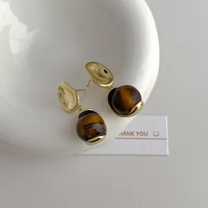 Golden earrings with irregular metal plates and polished round tiger eye stone pendants