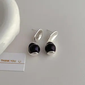 Detail showing silver irregular metal studs with glossy dark purple beads on a textured surface