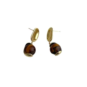 Elegant gold drop earrings featuring polished tiger eye stone charms on white background