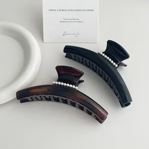 Détail de pinces à cheveux élégantes noires et écaille avec perles sur un plateau