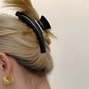 Détail de la pince à cheveux en acétate noir avec perles et maintien solide de la coiffure