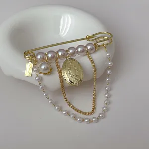 Vintage gold safety pin brooch with pearls, tassel chains and an oval locket pendant
