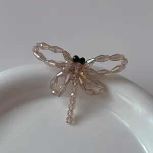 Détail d'une broche libellule perlée champagne avec des cristaux à facettes