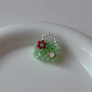 Macro d'une broche en forme de sac en perles vert clair avec une fleur rouge artisanale