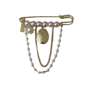 Vintage gold brooch with layered pearl tassels and oval locket on white background