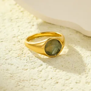 18K goud vergulde roestvrijstalen ring met groene natuursteen op een getextureerde zandgrond