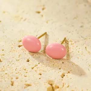 Detailed close-up of pink oval drip oil stud earrings on beige stone texture surface