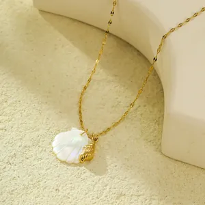 Gros plan du collier doré avec pendentifs coquillage et conque sur fond texturé
