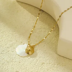 Collier doré avec double pendentif en coquillage et nacre sur fond de sable texturé