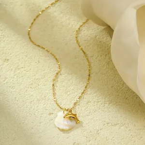 Détail du collier de plage avec pendentif coquillage et dauphin doré sur une pierre