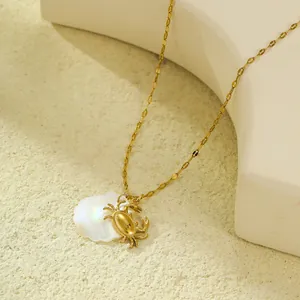 Détail macro d'un pendentif crabe doré et coquillage blanc sur une chaîne fine