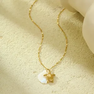 Détail du pendentif tortue dorée et coquillage blanc naturel sur chaîne gourmette dorée