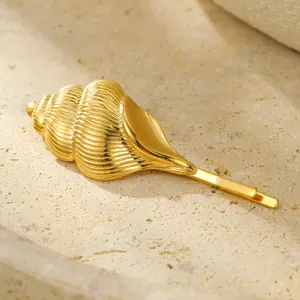 Golden conch shell hair clip with pearls on stone background for a luxury beach style