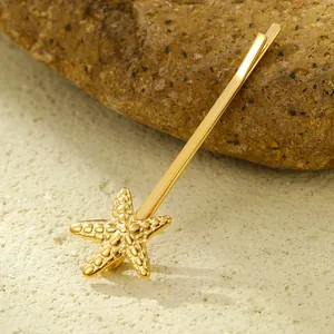 Detailed view of a golden starfish hair clip with textured details on a natural stone surface