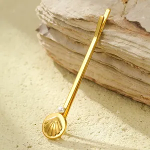 Detail of a gold seashell hair clip with a white pearl on a natural stone background