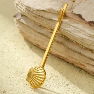 Detailed view of a gold shell hair clip with fine radial stripes on a warm stone background