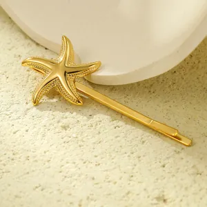 Detailed view of the gold-plated starfish hair clip with fine metal textures on white sand
