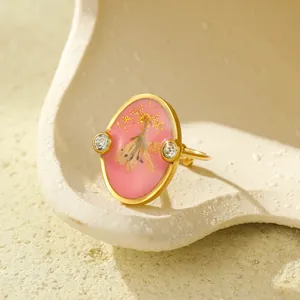Dettagli dell'anello con fiori secchi rosa con scaglie dorate e pietre di zircone
