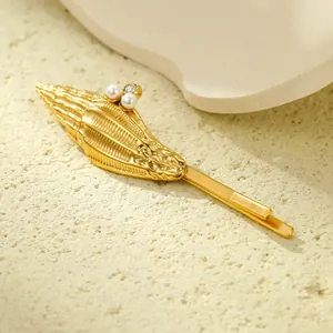 Golden seashell hair clip with pearls and starfish detail on a minimalist sandy background