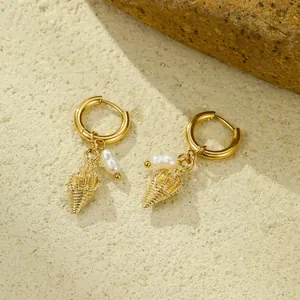 Gold ocean style hoop earrings with conch and pearl pendants on a natural stone background