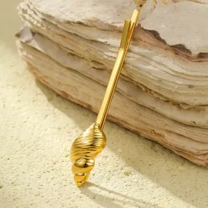 Macro shot of a golden shell hair clip resting on natural shale stones with warm lighting