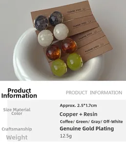 Close-up of four pairs of resin teardrop earrings in cream, green, amber and grey