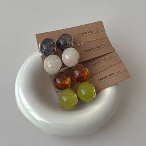 Detailed set of four pairs of resin marble texture stud earrings on kraft paper card