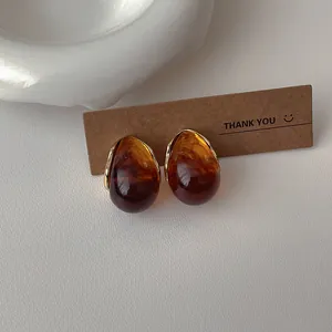 Macro shot of French vintage amber resin teardrop earrings with elegant gold metal base
