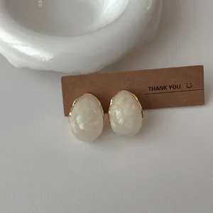 Detailed shot of resin teardrop earrings with gold metal edges and marble texture