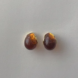 Detailed macro view of amber resin teardrop earrings with elegant golden metal base