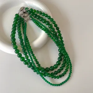 Collana di perle in calcedonio verde con fibbia in argento su un piatto in ceramica
