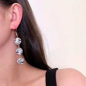 Longues boucles d'oreilles rétro en bois zébré portées par un mannequin au style chic