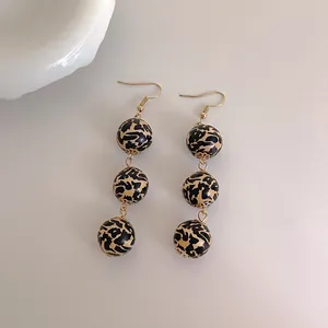 Détail macro de perles en bois léopard sur boucles d'oreilles pendantes avec crochets dorés