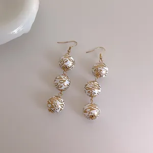 Boucles d'oreilles pendantes avec perles en bois blanc et doré au motif léopard
