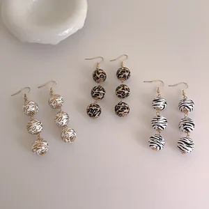 Détails de boucles d'oreilles pendantes en perles de bois avec motifs léopard et zèbre