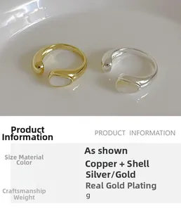 Detailed view of fluid design shell rings in gold and silver finish on ceramic plate