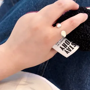 Detail of silver open ring featuring a metal bead and inlaid pebble charm on hand