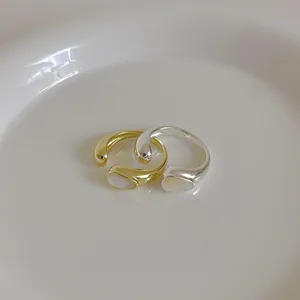 Set of gold and silver minimalist shell inlay open rings on a white ceramic plate