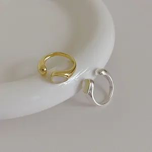 Minimalist gold and silver open rings with shell inlays on a white ceramic plate