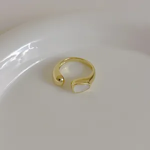 Close-up of minimalist gold shell ring with polished metal sphere and white inlay