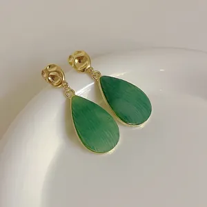 Détail de boucles d'oreilles goutte d'eau avec texture marbre vert et métal doré martelé