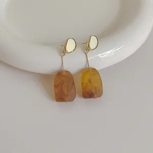 Detail of vintage resin drop earrings with amber tortoise texture and golden metal