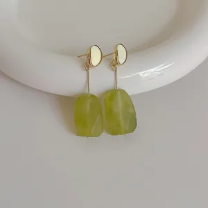 Detail of vintage geometric earrings with green resin pendants and gold metal finish