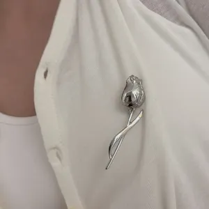 Silver tulip flower brooch pin in minimalist metal design on white knit cardigan