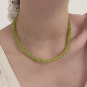 Elegant beaded necklace with round light green agate beads worn as a choker