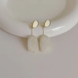 Macro detail of retro resin drop earrings with cream enamel and s925 silver needles