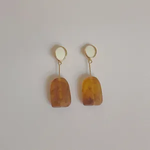 Detail of vintage geometric earrings with amber resin drop and white enamel top