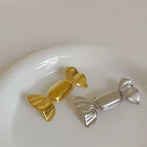 Macro view of polished gold and silver candy-shaped metal brooches on white plate