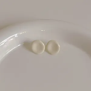 Detailansicht der cremeweißen runden konkaven Ohrringe im minimalistischen Keramik-Stil