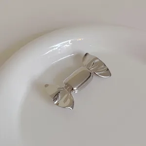 Macro detail of a silver candy-shaped metal brooch with polished mirror finish surface
